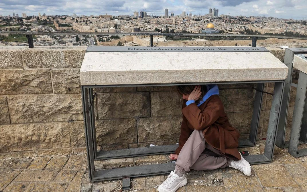 Война уже началась: МИД Эстонии срочно призывает покинуть Израиль — воздушное пространство закрыто: Женщина в Иерусалиме прячется во время воздушной тревоги.