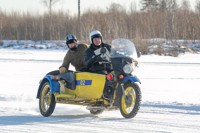 Два человека на мотоцикле с коляской, движущиеся по замерзшей поверхно